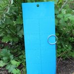 Blue garden kneeling pad leaning against green foliage.